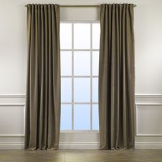 an empty room with a large window and two curtains hanging on the side of it