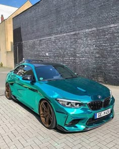 a blue car parked in front of a brick wall