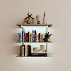 the shelves are filled with books and vases on top of each other in front of a white wall