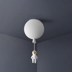 a pink lamp hanging from the ceiling next to a white teddy bear in an astronaut suit