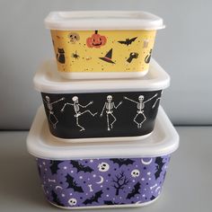 three plastic containers with halloween designs and skeletons painted on the lids are stacked in front of each other