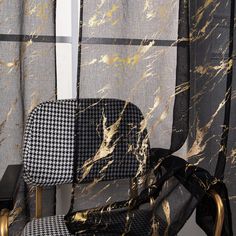 a black and white chair sitting in front of a window next to a checkered curtain