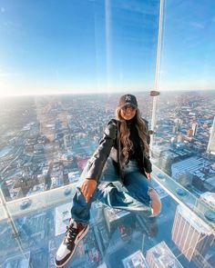 a woman sitting on top of a tall building