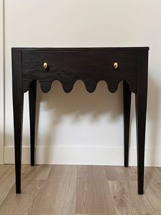 a small black table with two drawers on one side and gold knobs on the other