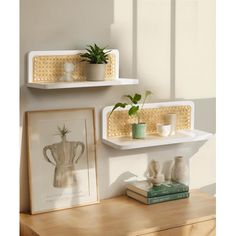 two white shelves with plants and pictures on them