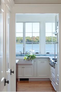 a kitchen with white cabinets and wooden floors