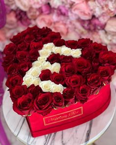 a heart shaped box filled with red and white roses