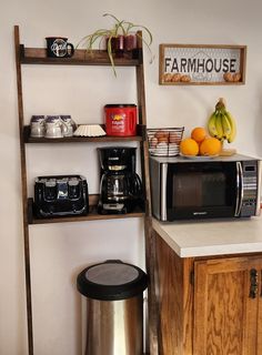 a kitchen area with a microwave, coffee maker and oranges