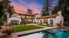 a large house with a pool in front of it and trees on the other side