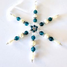 a snowflake ornament made out of glass beads and pearls on a white background