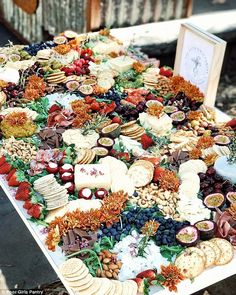 a table topped with lots of cheese and crackers next to a pile of fruit