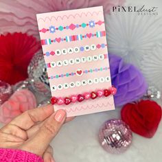 a hand holding up a card with beads on it and the words bead my valentine