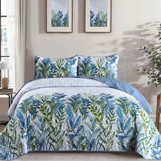 a blue and green comforter set with two pictures on the wall in front of it