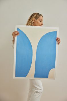 a woman holding up a large blue and white print with an abstract design on it