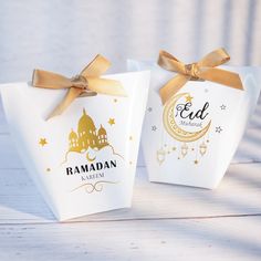 two small white bags with gold ribbons tied around them