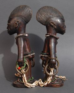 two wooden statues with chains and beads on them