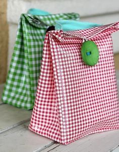 two green and red bags sitting on top of a white table next to each other