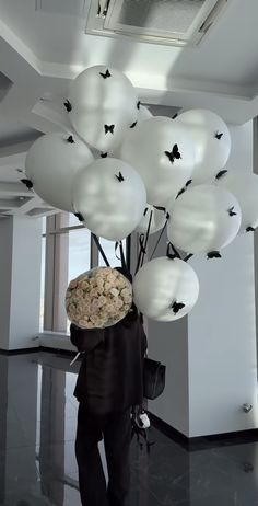 a man holding a bunch of balloons in his hand and some butterflies on the ceiling