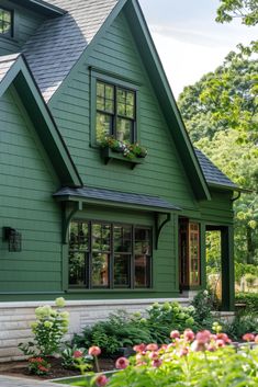 a green house with lots of windows and flowers in the window boxes on the front