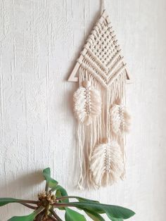 a white wall hanging next to a potted plant