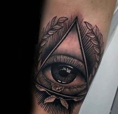 an all seeing eye tattoo on the right arm with leaves around it and a triangle in the center