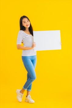 a young woman holding a white board in her hands and smiling at the camera on a yellow background