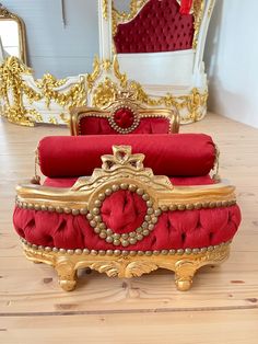 a red and gold couch sitting on top of a wooden floor next to a mirror