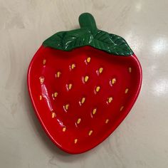 a ceramic strawberry shaped dish with green leaves on it's top and yellow dots on the bottom