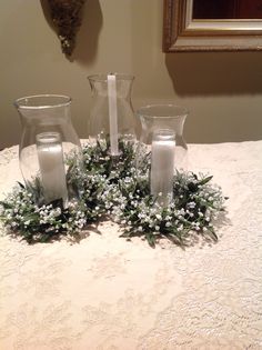 three glass vases sitting on top of a table covered in flowers and greenery