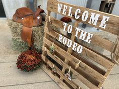 a wooden sign that says welcome to the rodeo with a cow statue in front of it