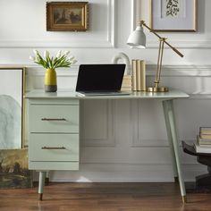 a laptop computer sitting on top of a desk next to a vase with flowers in it