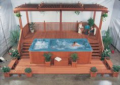 an above ground hot tub in the middle of a wooden deck with potted plants