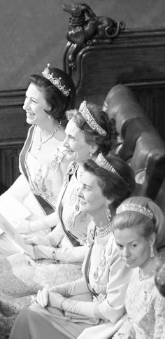 several women in dresses and tiaras sitting on a couch with one woman looking off to the side