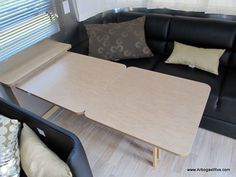 a couch and table in a small living room with wood flooring on the side