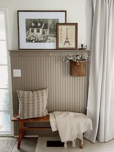 a bench with a blanket and some pictures on the wall above it next to a window