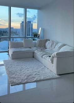 a large white couch sitting in front of a window next to a rug on the floor