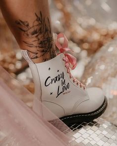 a close up of a person's legs with tattoos on them and white boots