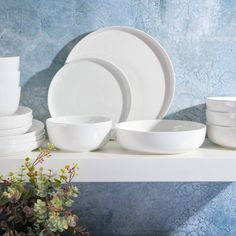 white dishes and cups are sitting on a shelf