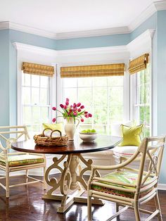 a dining room table with four chairs and a vase filled with flowers on top of it