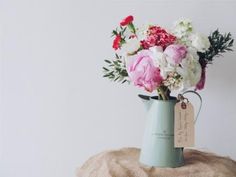 a vase filled with pink and white flowers sitting on top of a burlock