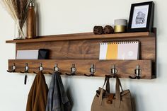 a wooden shelf with hooks and coats hanging from it's sides next to a purse