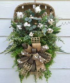 a wreath hanging on the side of a building with flowers and greenery in it