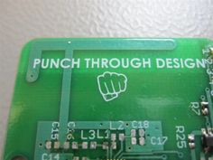 an electronic circuit board with the words punch through design on it and a hand holding a screw