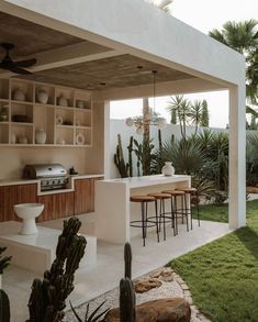 an outdoor kitchen and dining area with cactus in the background