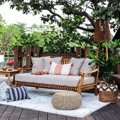 an outdoor seating area with wooden furniture and plants on the deck, surrounded by greenery