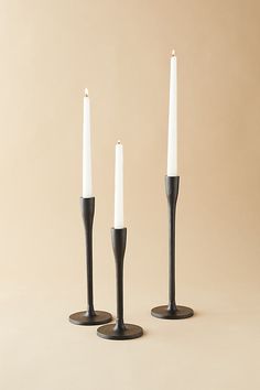 three black candles are standing next to each other with one candle in the middle and two white candles on top