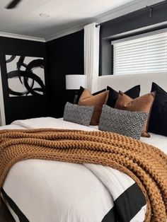 a white bed topped with lots of pillows next to a black and white bedroom wall