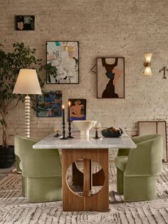 a dining room table with green chairs and pictures on the wall behind it in an apartment