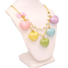 A cute and sweet statement necklace for Valentine's Day or lovecore season! This kawaii charm necklace includes Five heart shaped macaron ( macaroon ) pendants in pastel shades with a pearly finish and whipped cream center. Each necklace includes five 1" (2.5 cm) size charms hanging on a two-layered chain necklace with glass pearls on your choice of a 21" gold plated or silver plated chain. Accented with a baby pink fabric ribbon bow on one side. Necklace will be finished with a Fatally Feminine Pastel, Kawaii, Kawaii Lovecore, Jelly Jewelry, Lovecore Clothes, Kawaii Valentines Day, Necklaces Pink, Kawaii Valentine, Kawaii Necklace