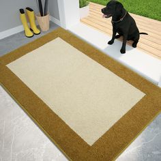 a black dog sitting on top of a brown and white rug next to a pair of yellow boots